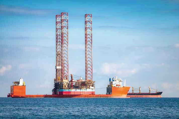 A jackup drilling rig at sea alongside a support vessel