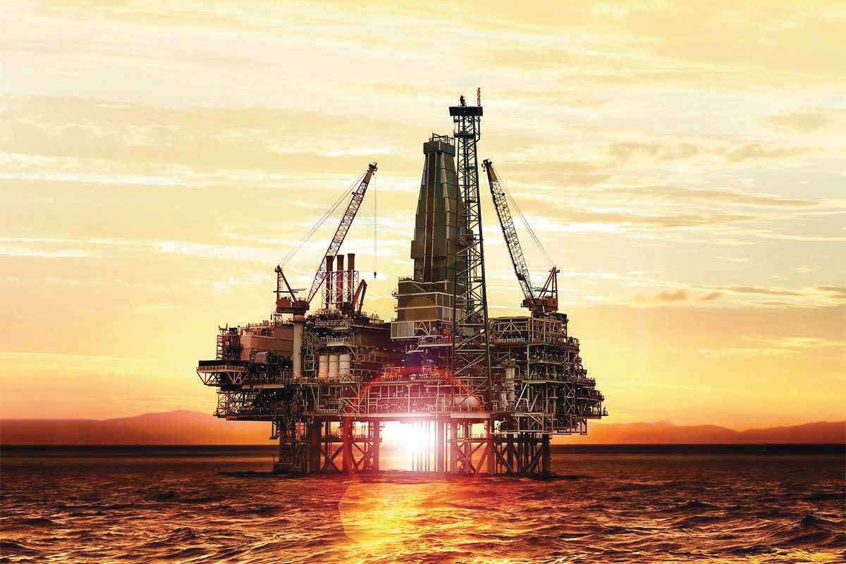 An offshore drilling platform silhouetted against a golden sunset